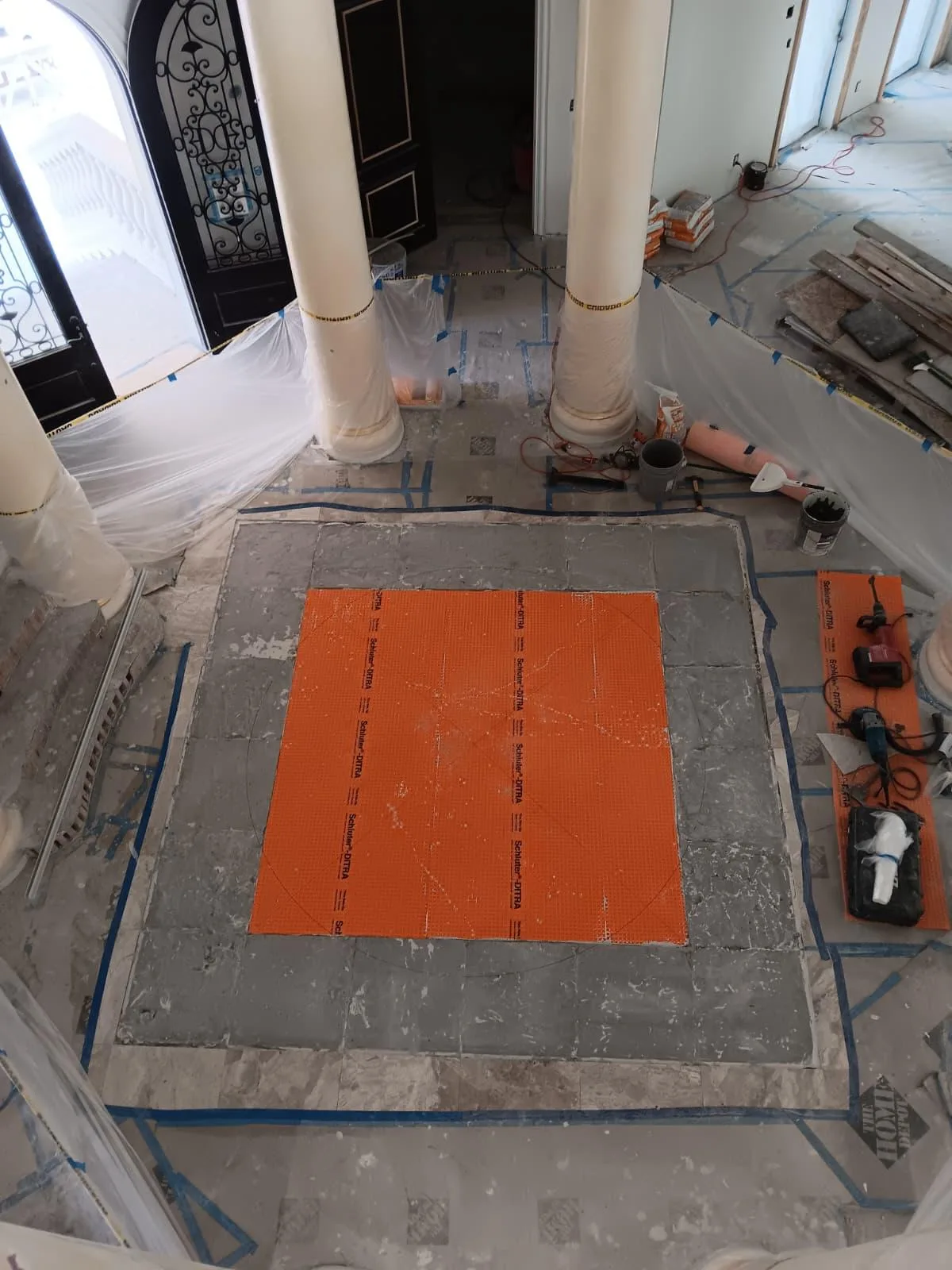 Orange membrane laid over the prepared floor area in an entry hall